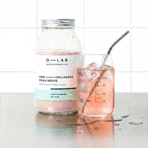 Flacon en verre Pro-Collagène Peau Neuve goût framboise D-LAB et verre glacé de boisson rosée avec glaçons et paille inox, plan de travail carrelé blanc